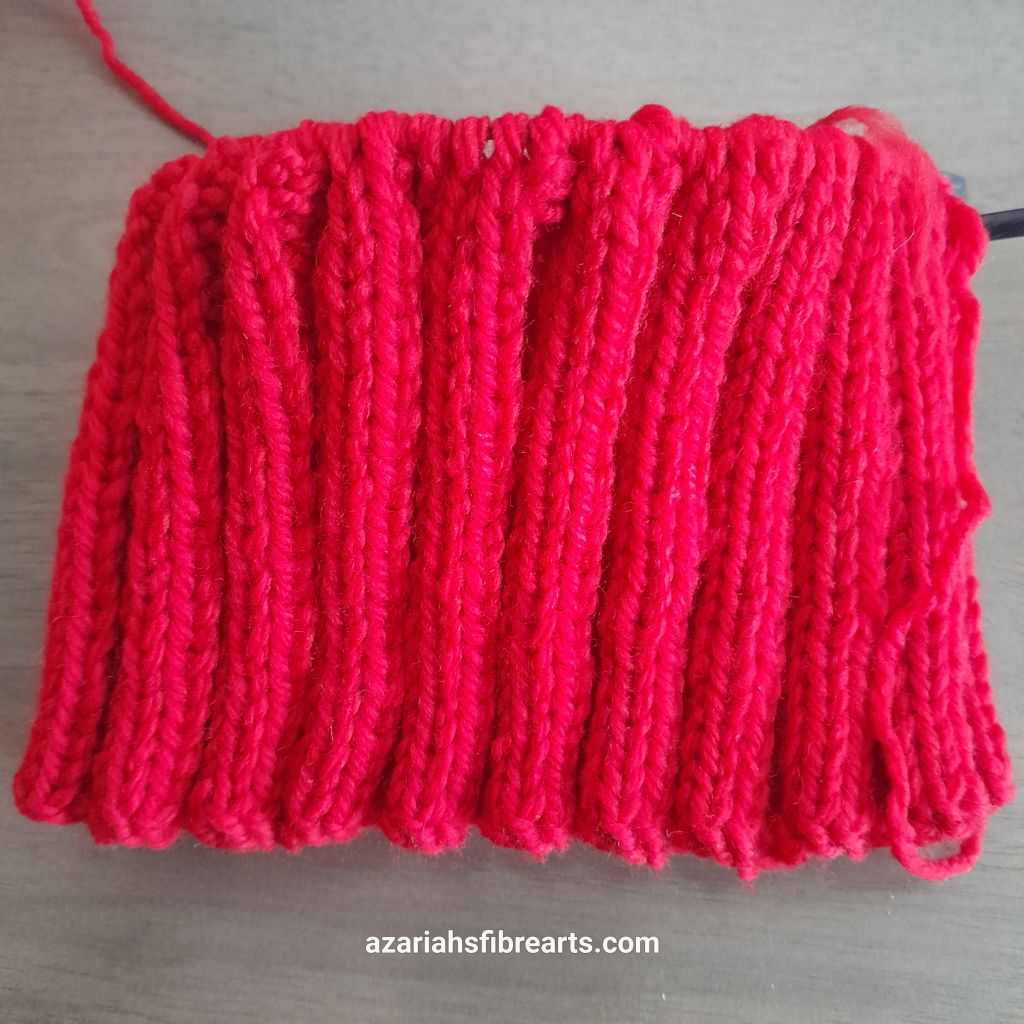 Close up of unstretched knitted rib pattern in red yarn.