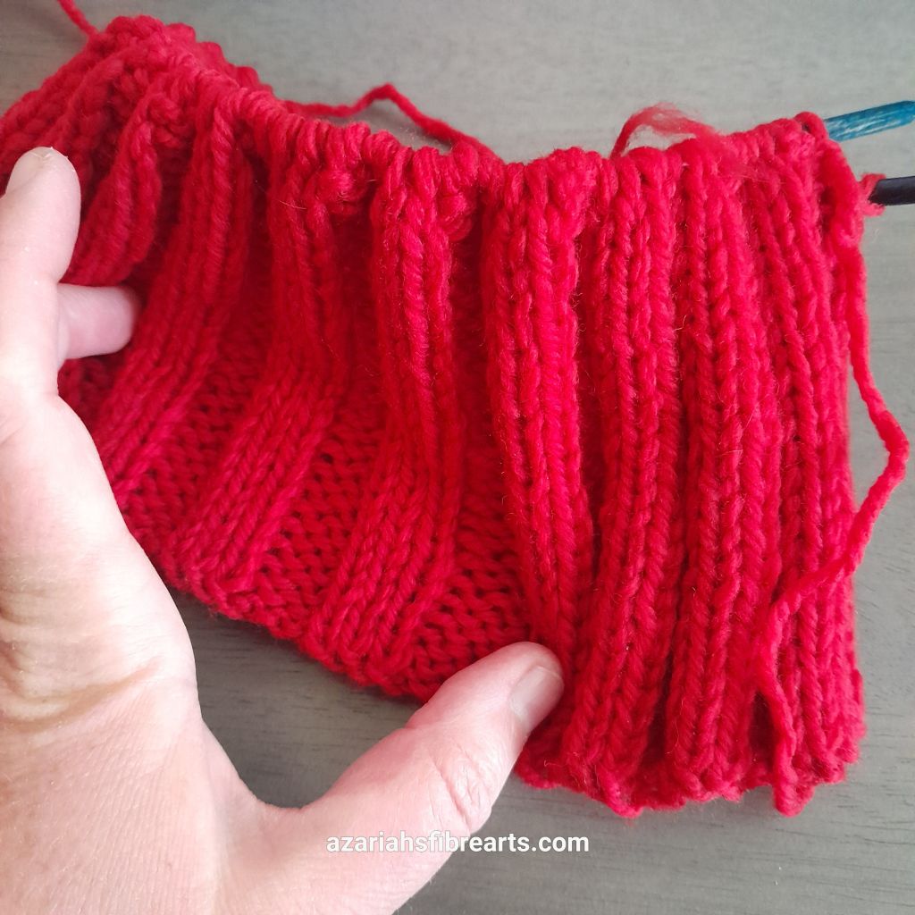 Close up of stretched knitted rib pattern in red yarn.